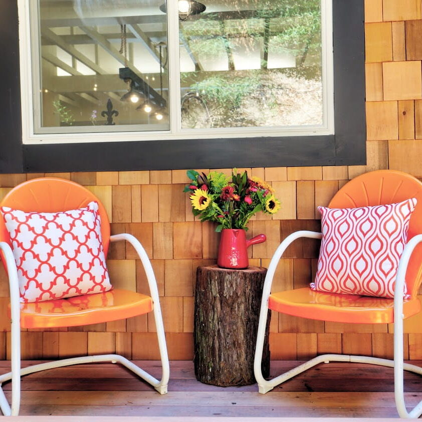 A colorful front porch with two cushioned chairs